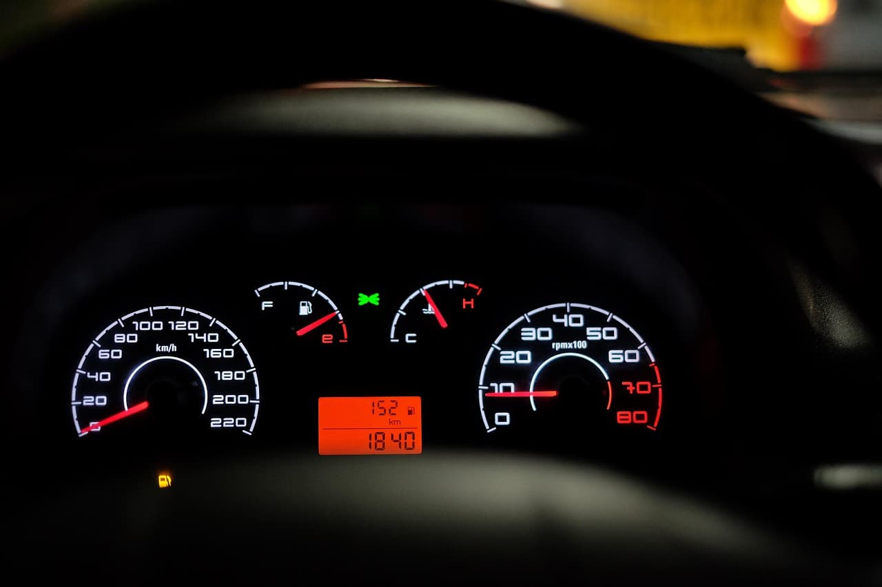 A car's instrument cluster glowing in the dark: speedometer, rev counter and warning lights